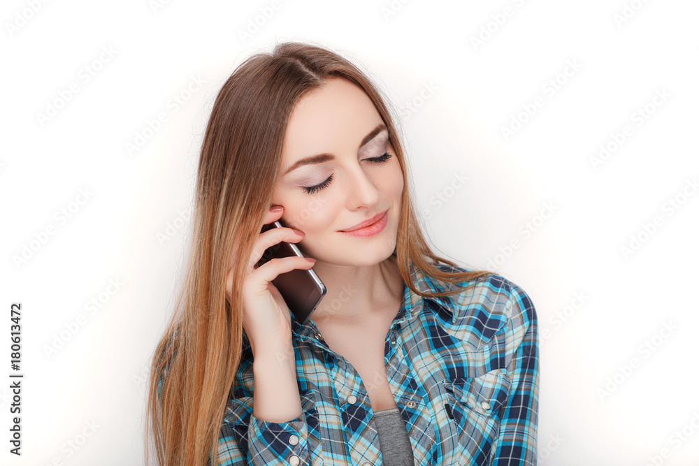Portrait of a young adorable blonde woman in blue plaid shirt enjoying having emotional conversation on smartphone. Portrait of a young adorable blonde woman in blue plaid shirt enjoying having emotional conversation on smartphone.