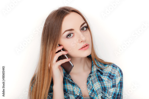 Portrait of a young adorable blonde woman in blue plaid shirt enjoying having emotional conversation on smartphone.