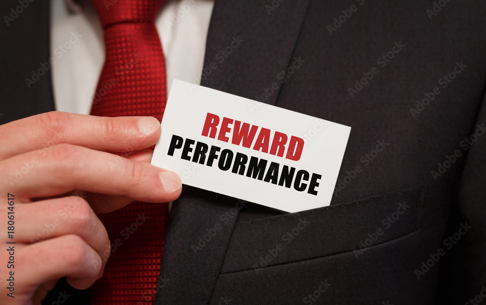 Businessman putting a card with text REWARD PERFORMANCE in the pocket Businessman putting a card with text REWARD PERFORMANCE in the pocket