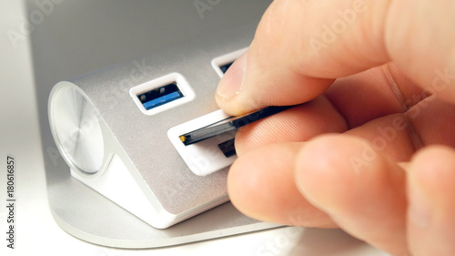 The hand inserts a USB flash drive into the card reader