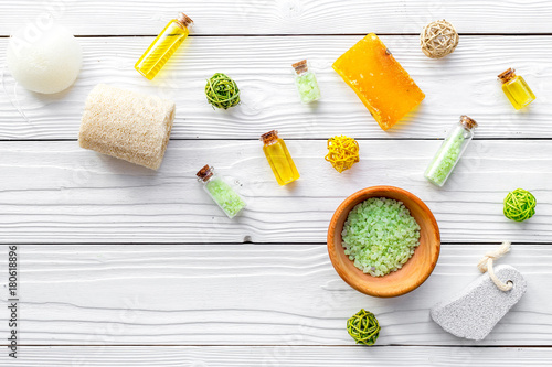 Foot spa cosmetics. Spa salt, pumice stone, soap and towel on white wooden background top view copyspace