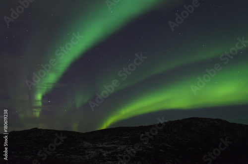 The Aurora in the night sky above the hills. © Moroshka