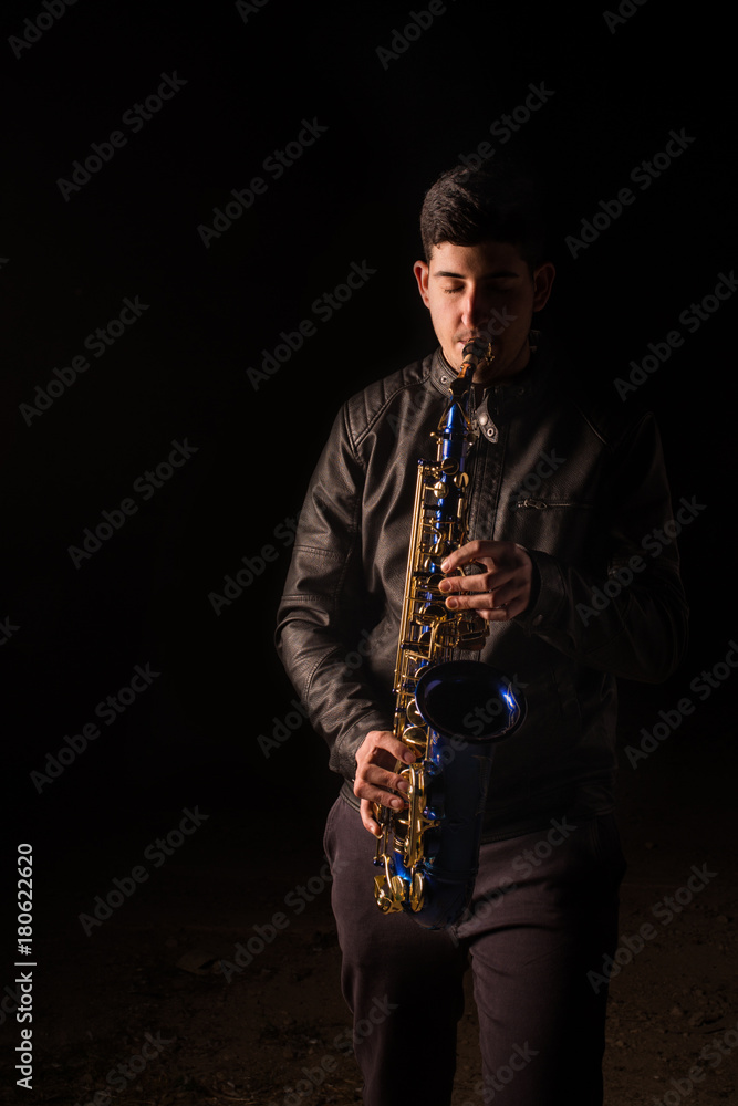 Naklejka premium Man playing saxophone, with black background