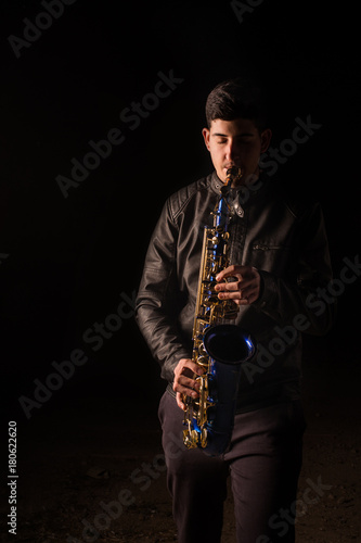 Man playing saxophone, with black background