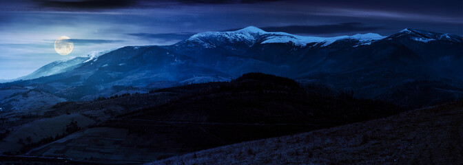 Leinwandbilder Schwarz great mountain ridge Borzhava with snowy tops at night in full moon light. beautiful countryside landscape in late autumn  © Pellinni