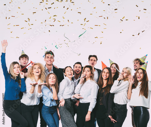 Happy smiling young people with gift boxes and blowing party whistles. photo