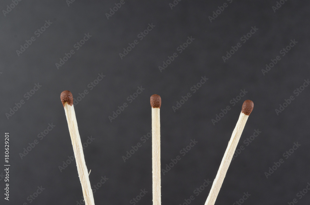 Three matches on a dark grey background Three matches on a dark grey background