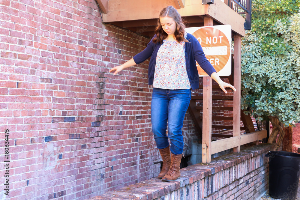 Girl Playing and Balancing on Red Brick Wall