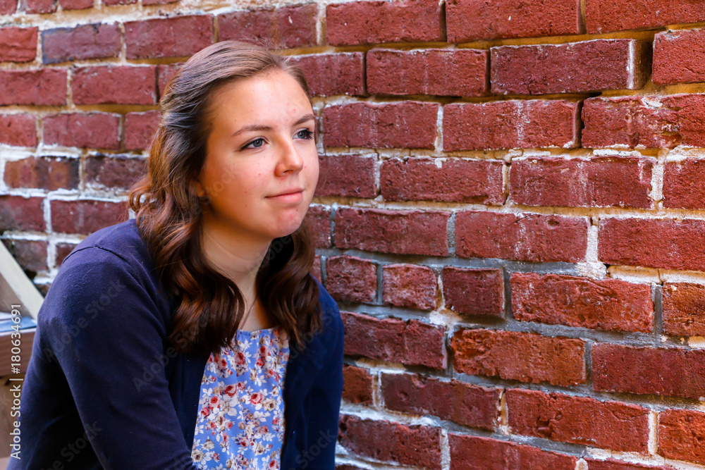 Girl Sitting on Stairway, Next to Red Brick Wall