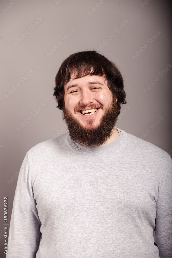 Fototapeta premium A happy man with a beard and dark hair, dressed in gray