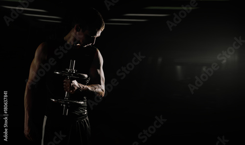 Strong Athletic Man Fitness Model Torso showing six pack abs. isolated on black background with copyspace Closeup of a handsome power athletic man bodybuilder doing exercises with dumbbell.