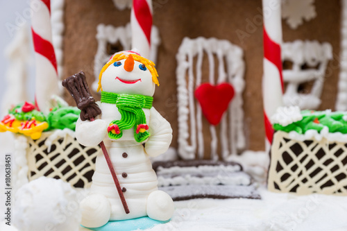 Close up of a snowman from sugar mastic near gingerbread house