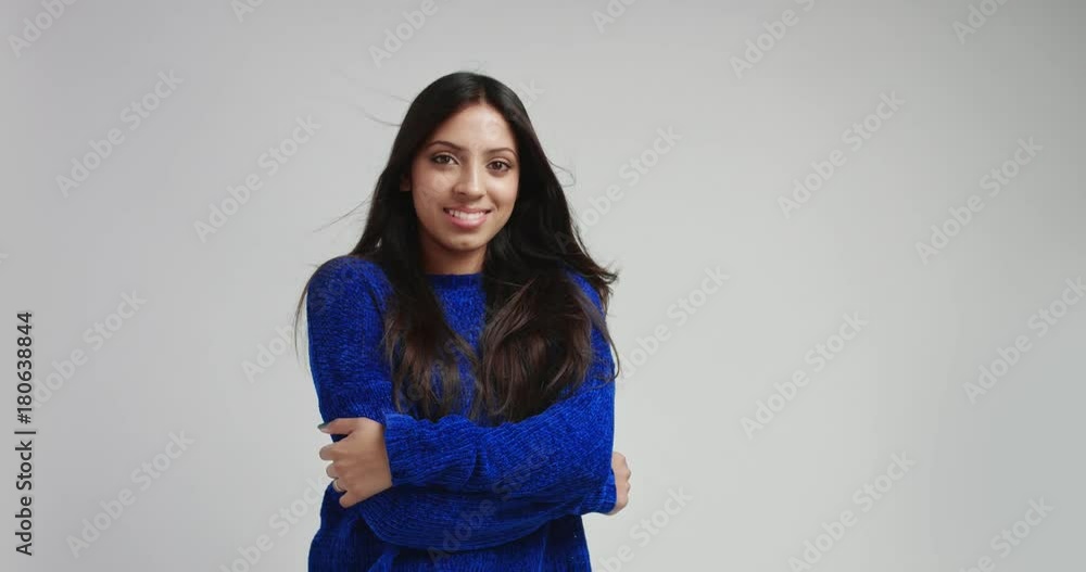 Seductive and dreamy latina girl with long black hair in a thick warm blue sweater moving in slow motion and smiling