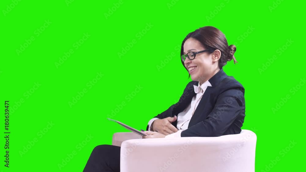 The TV Studio. Closeup of brunette in glasses. She sits in the Studio in a business suit and gives interviews. Green background. The TV Studio. Closeup of brunette in glasses. She sits in the Studio in a business suit and gives interviews. Green background.