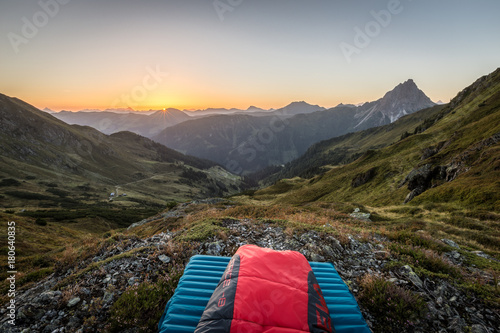 Aufwachen am Berg mit Schlafsack beim Sonnenaufgang im Sommer