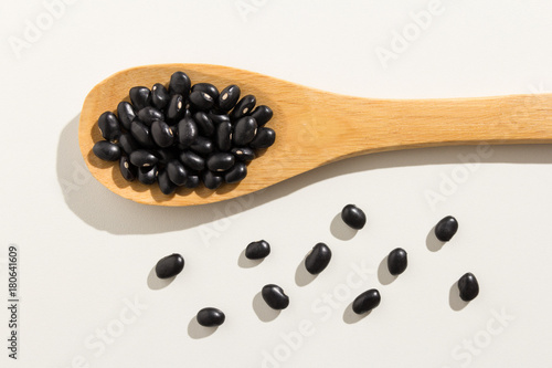 Black Turtle Bean legume. Healthy grains on a wooden spoon. White background.