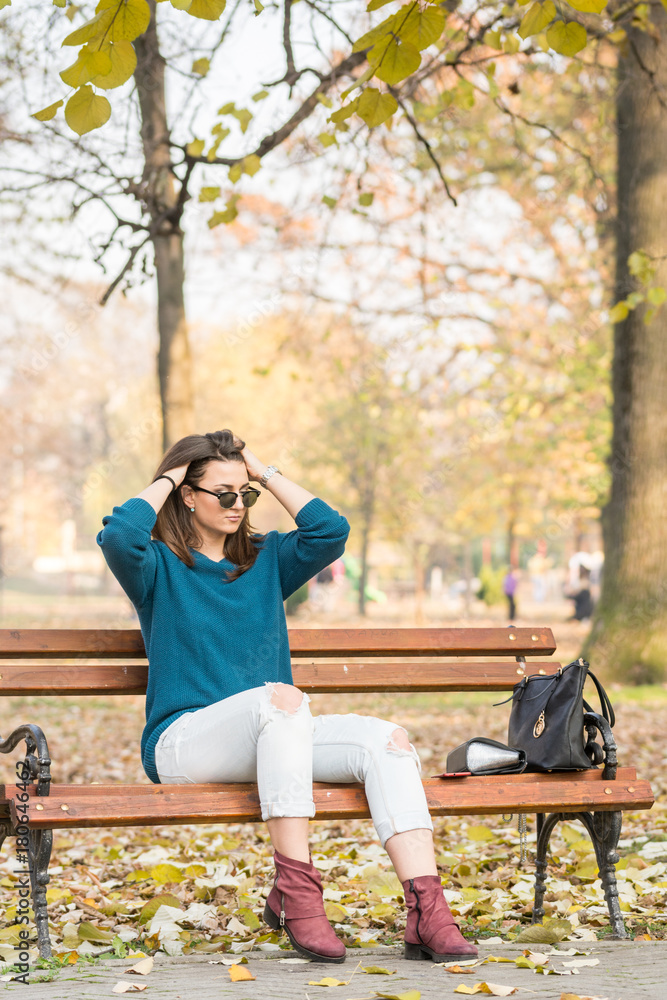 Φωτογραφία Young beautiful teenage girl sitting on the park bench and holding her hair