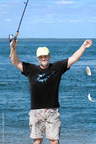 Fisherman with two fish on a fishing rod on the background of the sea. The pinfish, Lagodon rhomboides, is a saltwater fish of the Sparidae family, the breams and porgies photo