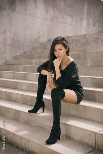 Beautiful exotic woman sitting on steps wearing high  heel boots
