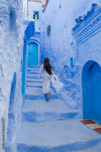 Beautiful girl in a white dress against a blue city Chefchaouen, Morocco © Olena Zn