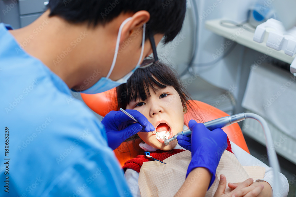 Dentist at work. Doctor cleaning little girl's teeth, close up. Pediatric dentistry, prevention dentistry concept Dentist at work. Doctor cleaning little girl's teeth, close up. Pediatric dentistry, prevention dentistry concept