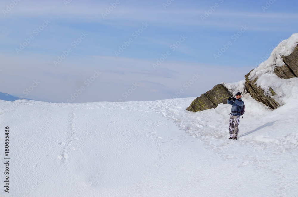 Young man standing outdoors in winter and making photo