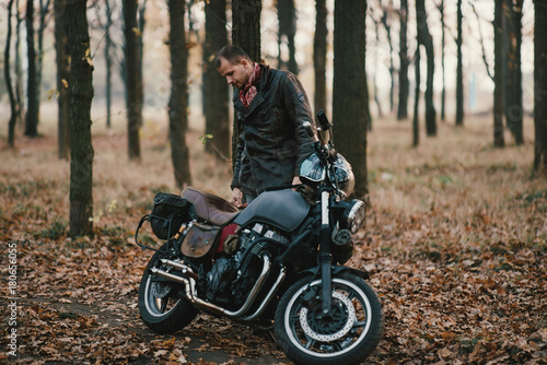 Man and old custom cafe-racer Motorcycle on forest 