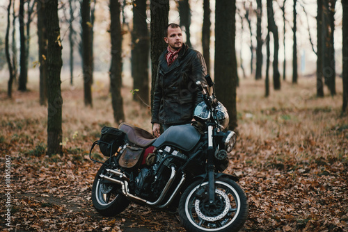 Man and old custom cafe-racer Motorcycle on forest 