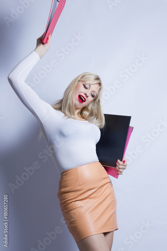 Business portrait of a beautiful young blond woman with long hair. The girl is dressed in a brown leather skirt and holds a folders photo