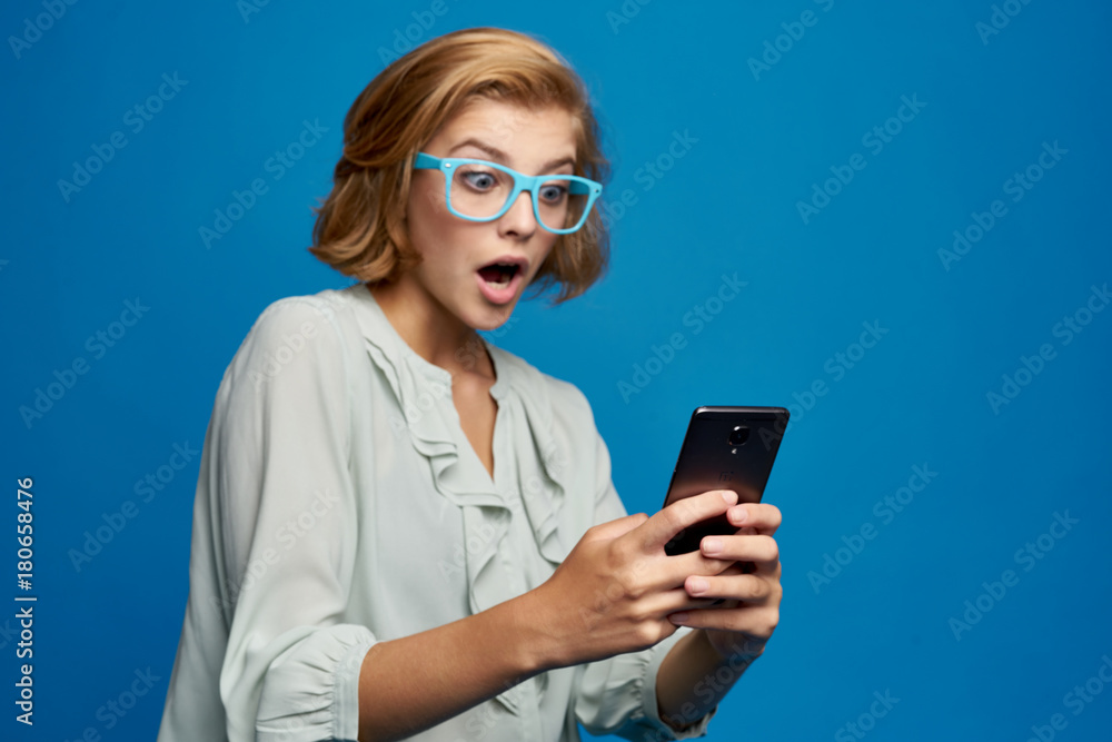 girl on a blue background is very surprised by the information on the phone