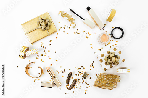 Frame with gift, sequins, makeup cosmetics kit and other accessories on white background. Composition in gold colors. Flat lay, top view.