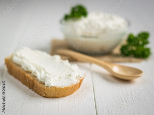 A piece of wheat bread neatly plastered cottage cheese cream on a white vintage table.