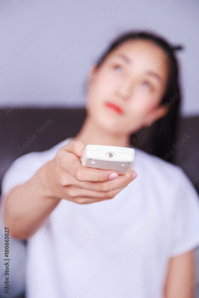 woman holding a remote control air conditioner on sofa at home woman holding a remote control air conditioner on sofa at home