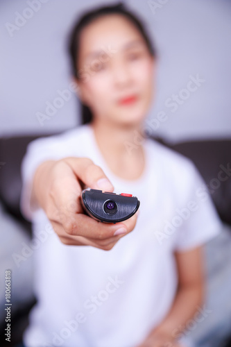woman with tv remote control on sofa at home