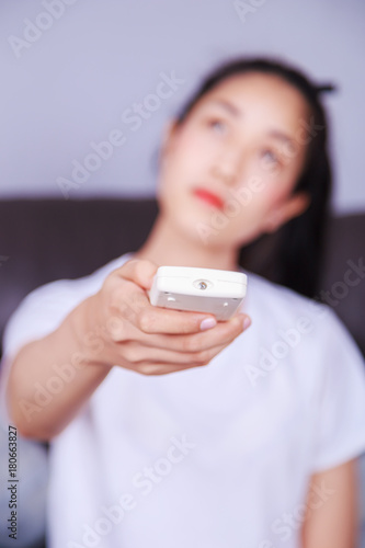 woman holding a remote control air conditioner on sofa at home