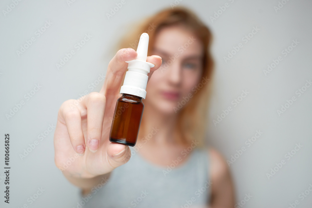 Fototapeta premium Treatment of a cold, the girl is holding a drop in hand
