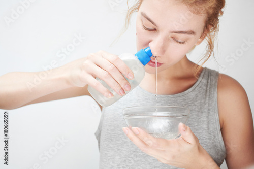 Treatment and prevention of the common cold. The girl washes out the nose with saline photo