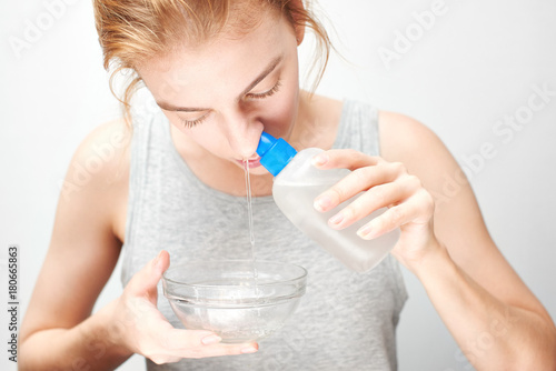 Treatment and prevention of the common cold. The girl washes out the nose with saline