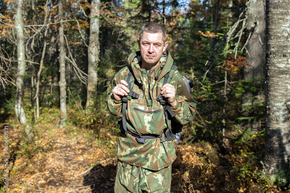 Tourist in camouflage clothes walking in the autumn forest