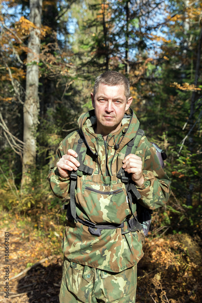 Tourist in camouflage clothes walking in the autumn forest