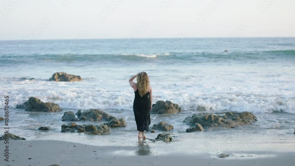 A girl walking up to the ocean in slow motion A girl walking up to the ocean in slow motion