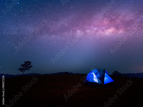 Camping. Blue tent glows under a night sky with milky way.
