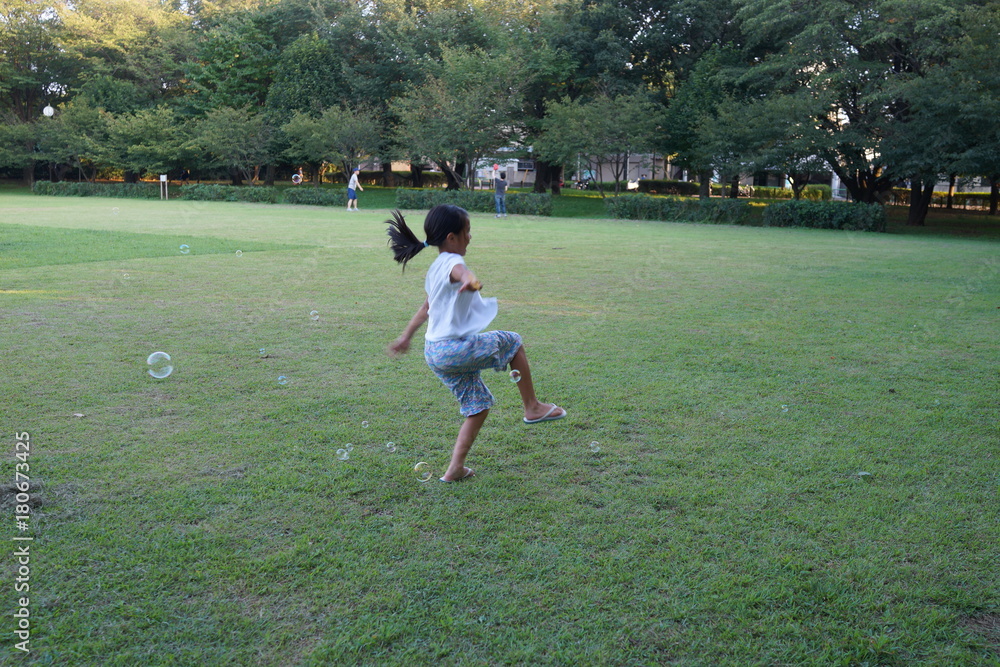 Fototapeta premium シャボン玉の中で踊る少女 躍動感 アジア人 公園 