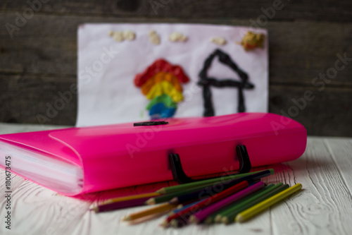 pink folder, colored pencils on a wooden table. photo