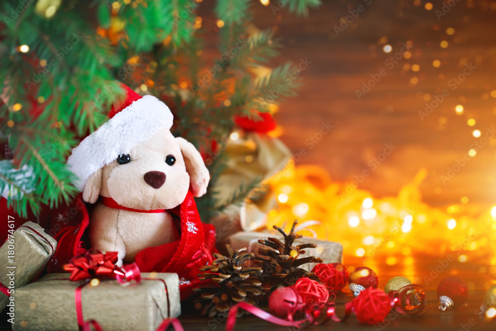 Obraz premium Christmas decoration, holiday plush dog with gifts under the Christmas tree. With New Year and Christmas.