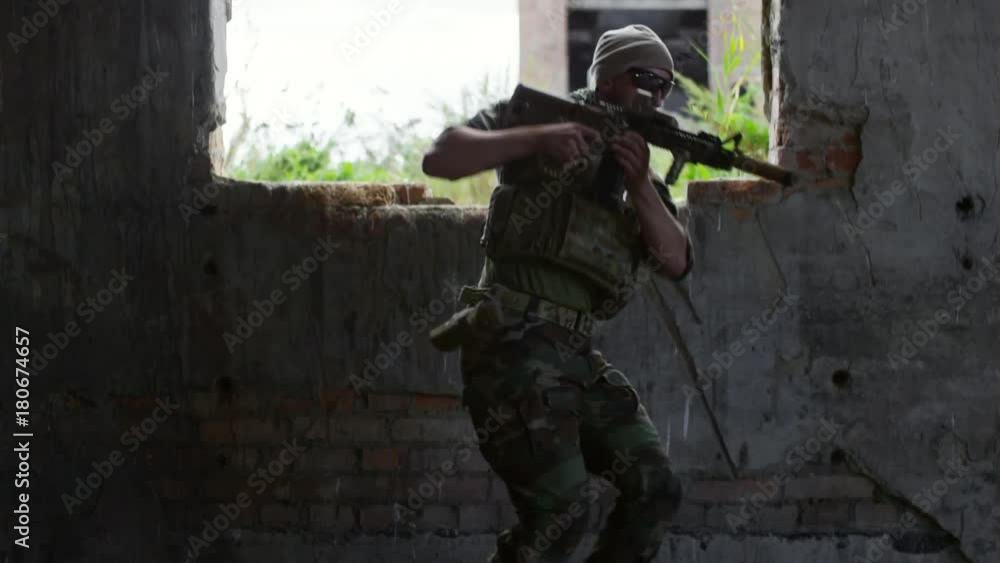 Tilt down of military soldier getting into destroyed building, looking around, walking towards the camera and aiming shotgun Tilt down of military soldier getting into destroyed building, looking around, walking towards the camera and aiming shotgun