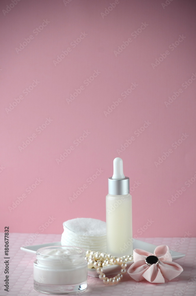 A jar of luxury beauty face cream and serum bottle with pearls on pink color background with copy space. Styled feminine lifestyle image.
A jar of luxury beauty face cream and serum bottle with pearls on pink color background with copy space. Styled feminine lifestyle image.