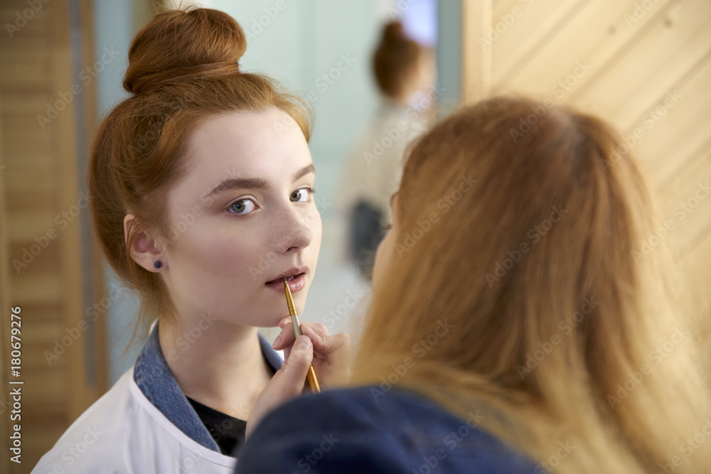 young woman doing make up for models before shooting. portrait of a young attractive redheaded woman in natural color. young woman doing make up for models before shooting. portrait of a young attractive redheaded woman in natural color.
