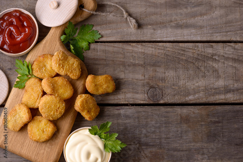 Chicken nuggets and sauces on wooden background