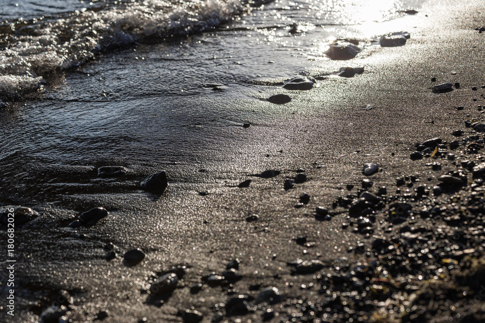 A close view of water on a lake shore, with details of sands and little stones A close view of water on a lake shore, with details of sands and little stones